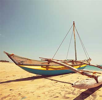 A sail boat rests on the tropical shores of Arugambay